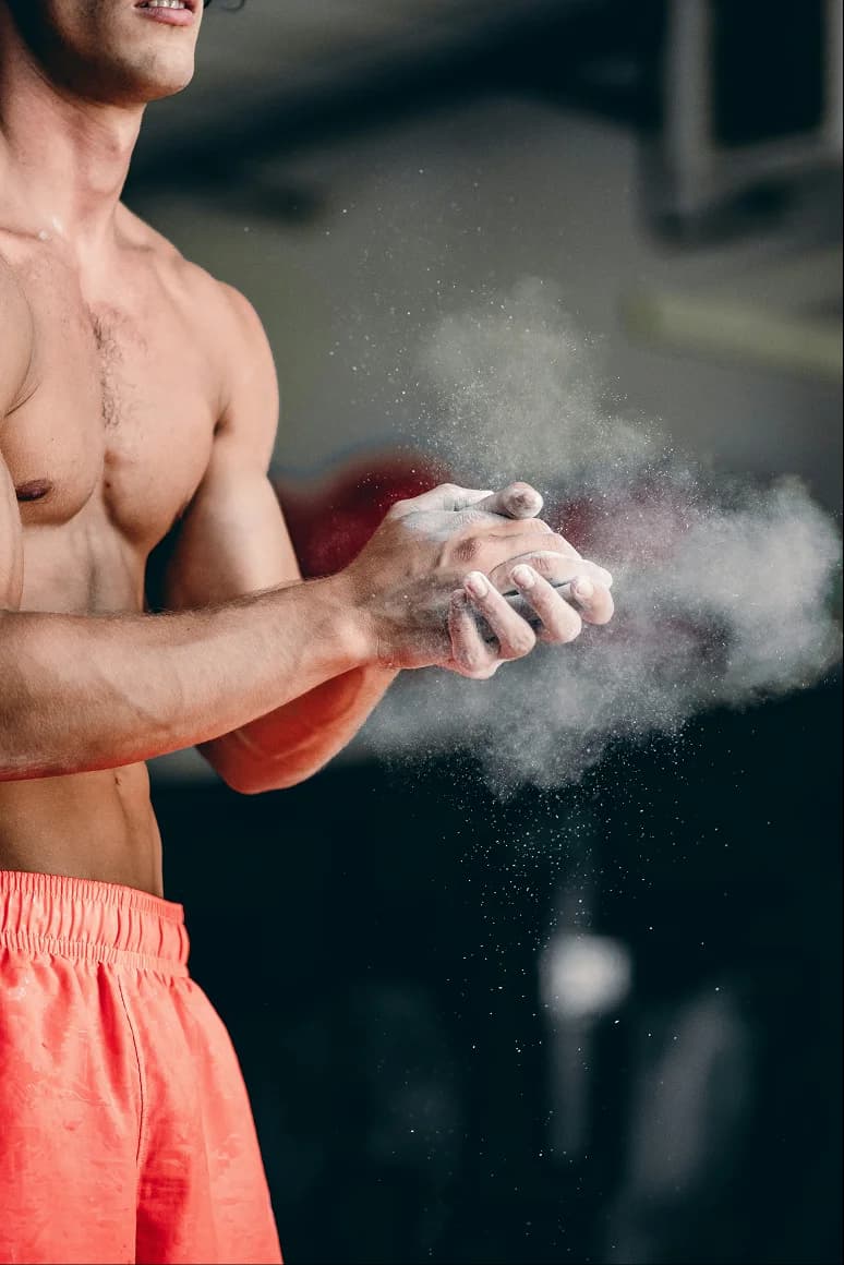 Athlete clapping chalk-covered hands sending up a cloud of chalk dust