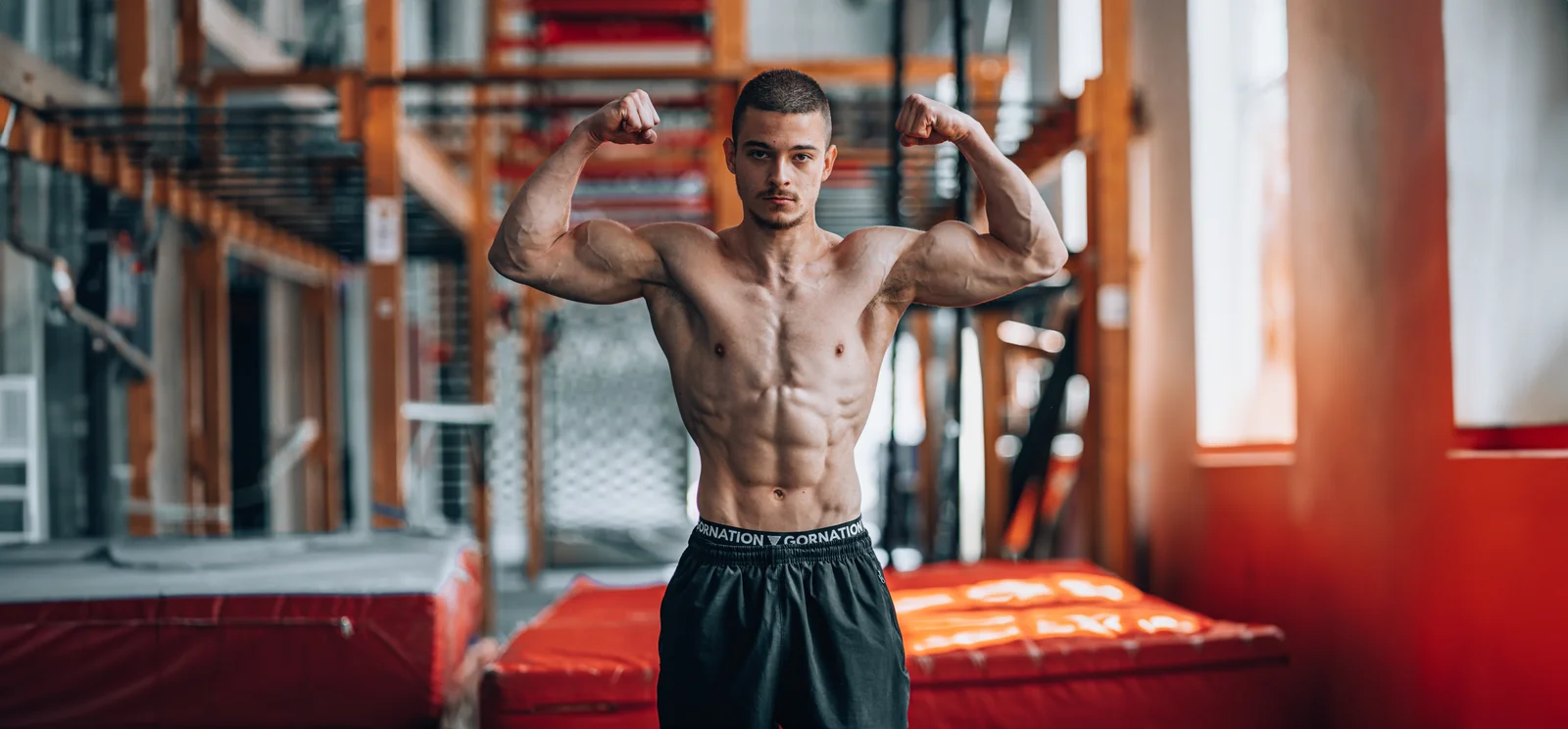 Daniel Hristov flexing a double biceps pose in a calisthenics gym