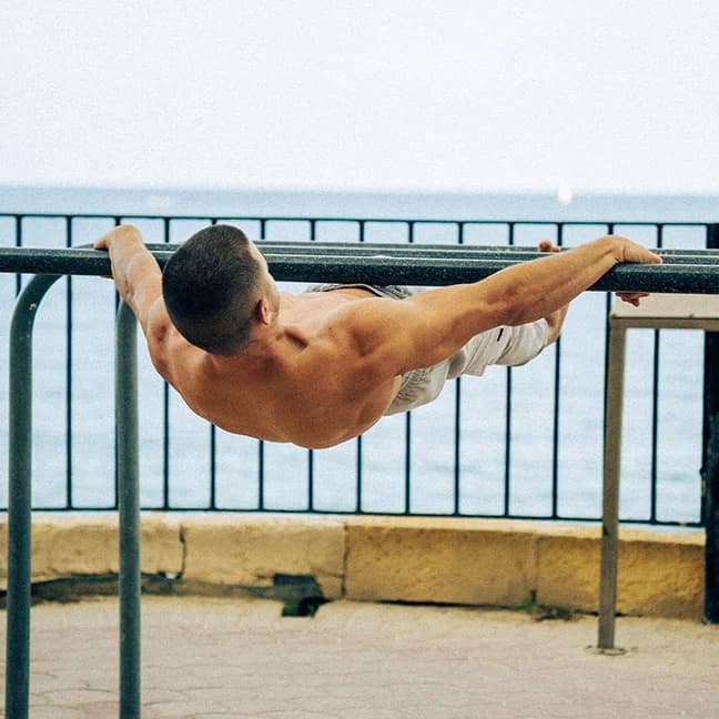 Daniel Hristov performing a front lever touch on a seaside railing
