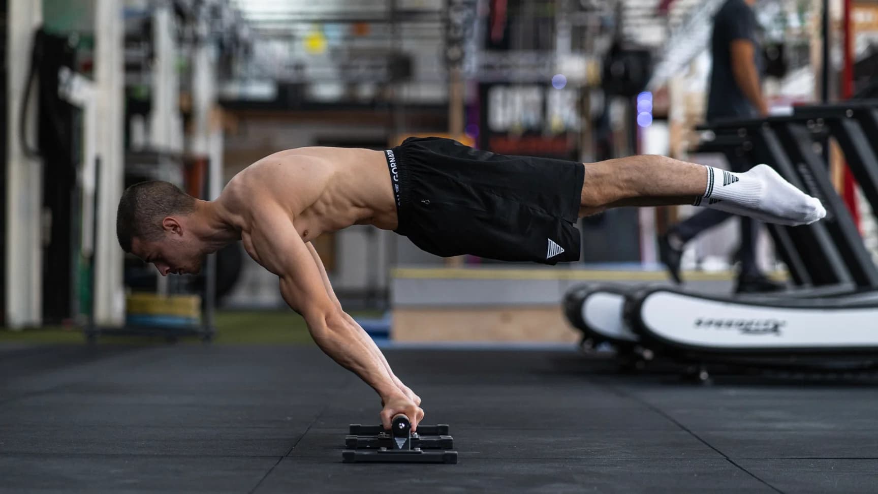 Daniel Hristov holding a full planche on a floor bar in a large training hall