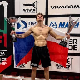 Calisthenics athlete Tomas Pospisil holding two trophies with the Czech flag at a world championship