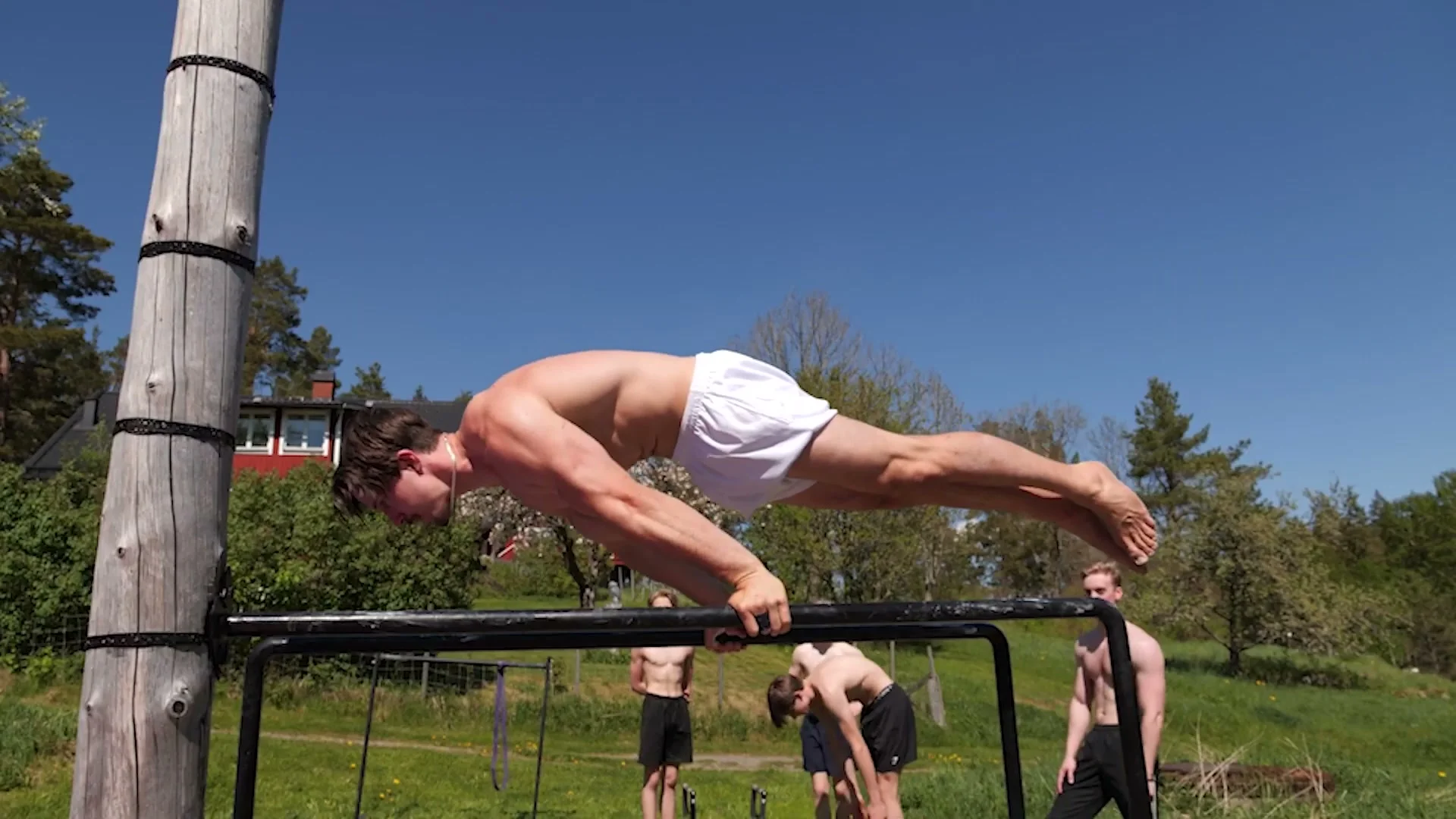 Daniel Hristov holding an L-sit dip position on portable parallettes outdoors