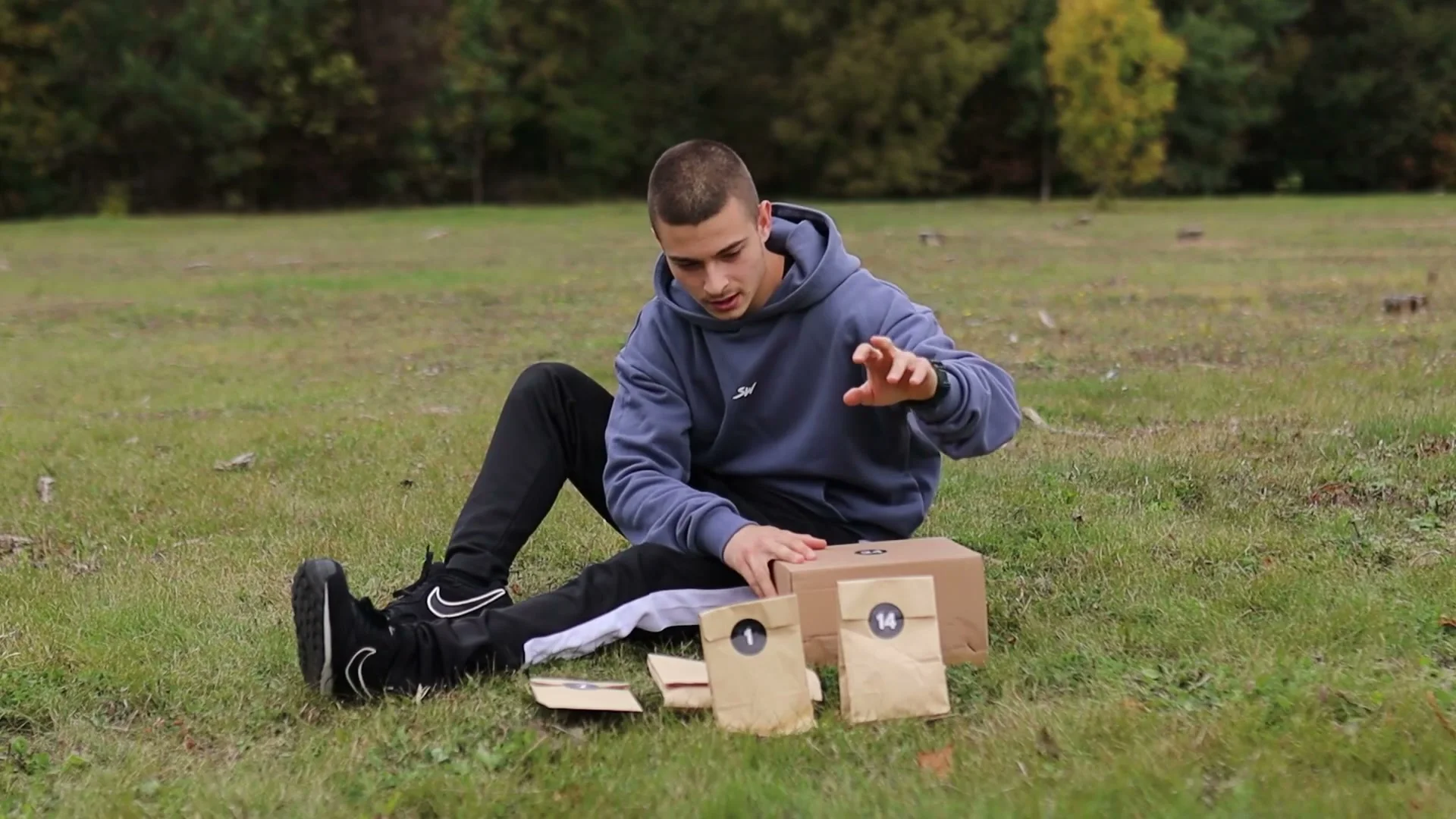 Daniel Hristov sitting on grass in front of six numbered GorNation advent calendar boxes before opening them