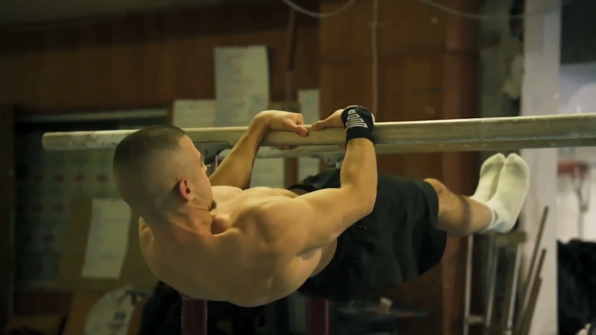An athlete pulling into a front lever touch position on a pull-up bar with a bent, compressed line