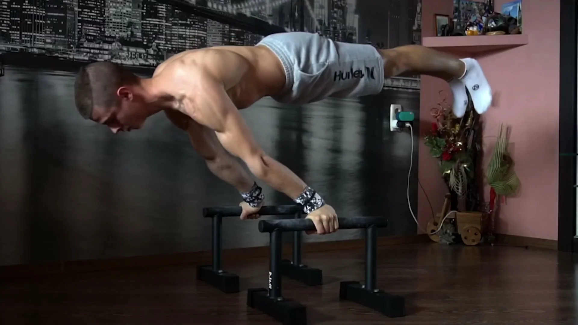 An athlete holding a full planche on parallettes with a straight, horizontal body line