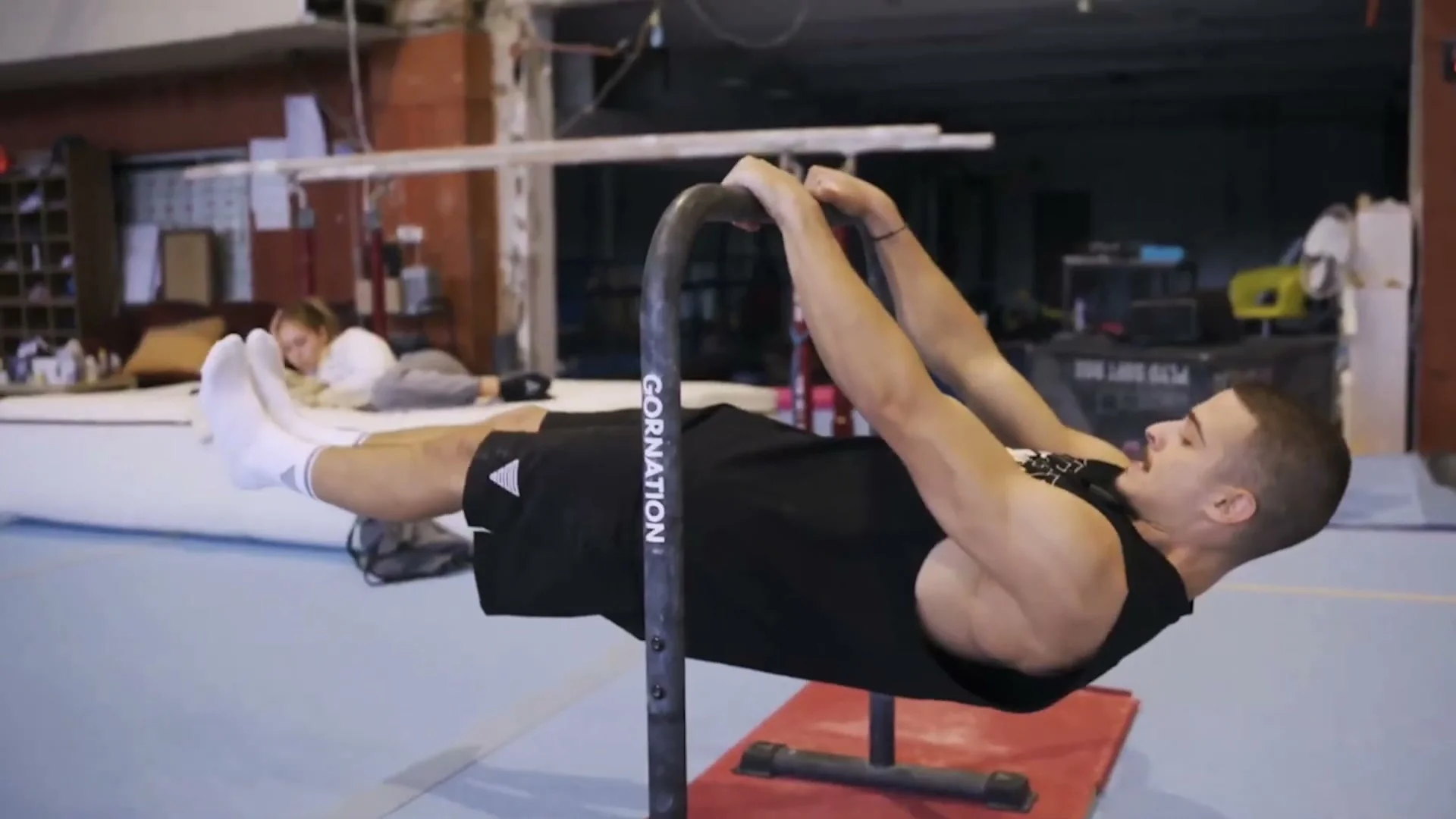 Daniel Hristov holding an isometric muscle up support position on a pull-up bar with elbows locked